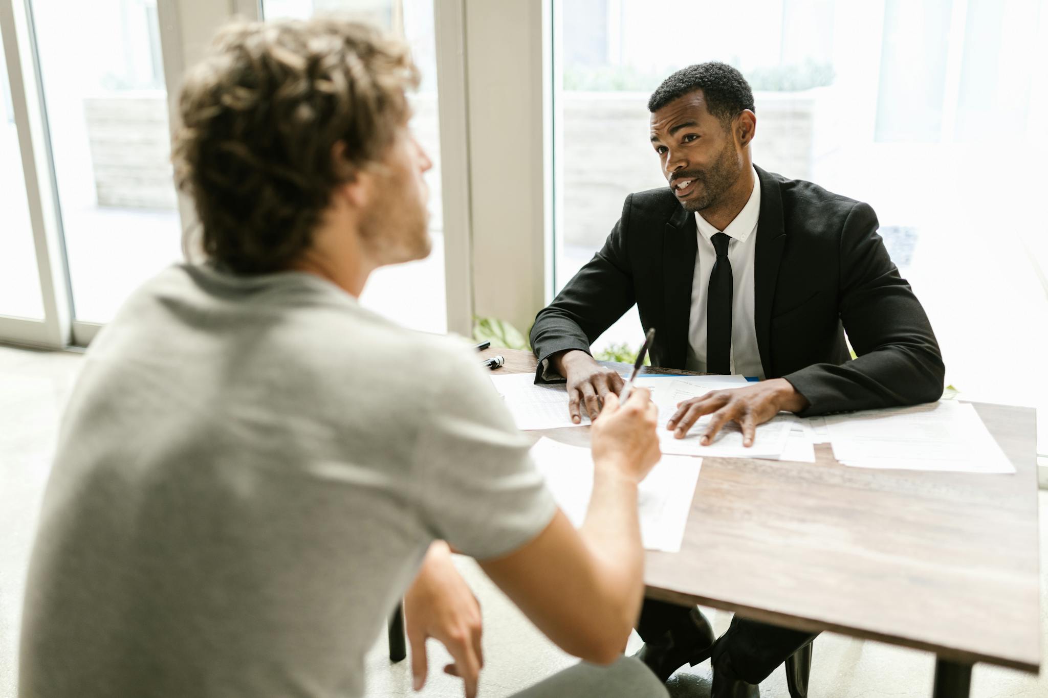 Two men having a discussion over documents in a modern office setting.